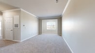 Located at 708 Glamorgan Way in Rock Hill, South Carolina, this single-floor home offers a well-organized layout with a clean, neutral aesthetic throughout. The living area features plush wall-to-wall carpeting, crown molding, and a seamless connection to the kitchen, which includes white cabinetry and a light countertop with a breakfast bar. The open flow between the kitchen and living space creates an inviting, functional environment.

The bedrooms are generously proportioned, each finished with soft carpeting, neutral-toned walls, and white baseboards. Multiple windows fitted with horizontal blinds allow ample natural light to filter in while offering views of the surrounding neighborhood. The primary bedroom stands out with its extra width, crown molding detail, and a large window bay that enhances the sense of space.

Two full bathrooms serve the home, both finished consistently with wood-look luxury vinyl plank flooring, white vanity cabinetry, light countertops, and a tub-shower combination. The bathrooms maintain a bright, clean appearance with modern fixtures and mirrors above the vanities.

A dedicated laundry area accommodates a full-size washer and dryer side by side, complete with wire shelving above for additional storage. The home's cohesive design, neutral palette, and practical features make it a comfortable and move-in-ready residence.