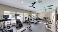 Located at 5525 N Stanton St in El Paso, Texas, this fitness center offers a comprehensive and well-organized exercise facility designed to support a full range of workout routines. The single-room space is finished with durable dark rubber flooring, smooth neutral-toned walls, and a white ceiling fitted with recessed lighting and a ceiling fan that promotes airflow and comfort during workouts.

Natural light flows in through multiple windows fitted with horizontal blinds, offering views of the surrounding outdoor greenery and creating an inviting atmosphere. Full-length wall mirrors run along a significant portion of the room, visually expanding the space and allowing users to monitor their form during exercise.

The cardio section is well-stocked with multiple treadmills, an elliptical trainer, a stair climber, and a stationary bike. Strength training is supported by a multi-station cable and pulley machine, ideal for a variety of resistance exercises. A dedicated free weights area features a tiered dumbbell rack with a broad selection of weights and an accompanying bench. A glass-paneled door provides easy access to the facility. Overall, the space maintains a clean, functional aesthetic that prioritizes usability, making it a practical and fully equipped destination for daily fitness.