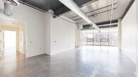Located at 512 Reily St in Harrisburg, PA, this 3-bedroom, 2-bathroom loft-style residence offers a striking industrial-modern aesthetic across a generously sized single-floor layout. Polished concrete floors flow throughout the entire unit, reflecting natural light and contributing to the space's clean, contemporary feel. The open living areas are defined by soaring ceilings with exposed ductwork and ductwork runs, lending an authentic urban loft character. Large floor-to-ceiling windows and expansive glass panels frame views of the surrounding Harrisburg cityscape, flooding the interior with abundant natural light. A modern fireplace adds a refined focal point to the living area. The kitchen is outfitted with rich dark-stained wood cabinetry, granite countertops, stainless steel appliances including a range, microwave, dishwasher, and refrigerator, complemented by track lighting overhead. The spacious primary bedroom features tall windows with city views and access to a well-organized walk-in closet with built-in wire shelving systems. The bathrooms are finished with polished concrete floors, dual-sink vanities with dark countertops, and full soaking tubs. The layout also includes a hallway connecting the private sleeping quarters to the main living areas, offering a functional and cohesive flow throughout.
