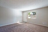 Located in San Leandro, CA, this well-appointed one-bedroom, one-bathroom unit offers a thoughtfully organized single-floor layout. The combined dining and living area is carpeted for comfort and features a ceiling fan overhead, creating a relaxed and functional gathering space. Natural light filters in through a window with blinds, offering a pleasant outdoor view of surrounding greenery.

The galley-style kitchen is a standout feature, showcasing crisp white shaker cabinetry, stone-look countertops, and light wood-style flooring. Black appliances — including a refrigerator, electric range, microwave, and dishwasher — provide a clean contrast against the bright cabinetry, making the kitchen both practical and visually appealing.

The bedroom is generously proportioned, finished with soft carpeting and a textured ceiling, and includes access to a dedicated closet. A second closet in the hallway provides additional storage. The bathroom is cleanly finished with a white vanity, stone-look countertop, large mirror, and a full tub-shower combination set against light tile flooring, maintaining the unit's consistent, updated aesthetic.

Throughout the space, neutral gray walls, white trim, and textured ceilings contribute to a clean, cohesive look. The efficient layout maximizes every square foot, making this a practical and comfortable home.