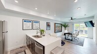 Located at 507 N Broadway in Farmington, Utah, this efficient single-floor space offers a well-planned layout that accommodates a fully equipped kitchen, two dedicated offices, and a full bathroom. The kitchen is a standout feature, showcasing dark gray shaker-style cabinetry, white quartz countertops, a classic subway tile backsplash, and a full suite of stainless steel appliances including a range, over-the-range microwave, and refrigerator. A peninsula with bar seating adds a practical gathering or break area. The two office spaces provide functional work environments with clean white walls and ample room for workstations and equipment, supporting focused productivity. One office features a ceiling fan and a large window that invites natural light and outdoor views. The full bathroom is well-appointed with a single-sink vanity with dark cabinetry, white quartz countertop, marble-look tile flooring, and a tub-shower combination. Light wood-look flooring flows throughout the main areas, lending a clean, modern aesthetic. The overall ambiance is bright, contemporary, and practical — well-suited for a small business, professional office, or creative workspace.
