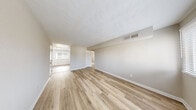 Located at 810 Lasalle Ave in Hampton, Virginia, this single-floor unit offers a clean, move-in-ready interior defined by consistent light-toned luxury vinyl plank flooring and a neutral color palette throughout. The open living areas are generously proportioned, with textured ceilings, crisp white baseboards, and multiple windows dressed with horizontal blinds that invite ample natural light into each room. The updated kitchen is a functional highlight, featuring white shaker-style cabinetry, light granite-style countertops, a stainless steel double-basin sink, and a full suite of appliances including an electric range with overhead microwave, a dishwasher, and a stainless steel refrigerator. A large window over the kitchen area frames outdoor greenery, adding a pleasant view while cooking. The bedrooms are well-sized and bright, each with windows offering exterior views and easy access to closet storage. A utility closet houses the water heater conveniently alongside additional storage space. The bathroom features a full tub-shower combination with clean white tile surround and chrome fixtures. Overall, the space presents a bright, well-maintained environment with practical updates suited for comfortable everyday living.
