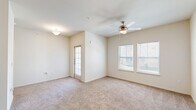 Located at 300 S Loop 288 in Denton, TX, this 1-bedroom, 1-bathroom unit offers a practical and comfortable single-floor layout designed to maximize functionality. The open living area features neutral-toned carpet, a ceiling fan with integrated lighting, and dual windows that invite natural light while providing views of the surrounding exterior. A glass-paneled door leads to an outdoor area, enhancing the sense of openness. The kitchen is efficiently designed with a galley-style configuration, featuring dark taupe cabinetry, light countertops, a full suite of black appliances including a refrigerator, electric range, built-in microwave, and dishwasher, as well as a peninsula with pendant lighting that separates it from the living space. A pantry provides additional storage. The bedroom is a comfortable, carpeted retreat with a ceiling fan and two closets offering ample storage. The bathroom features tile flooring, dark wood cabinetry with a vanity, a shower/tub combination, and clean, neutral finishes throughout. The overall color palette is light and airy, with warm beige tones creating a cohesive and inviting ambiance throughout the unit.