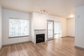 This single-floor residence offers a clean, modern layout designed for comfortable everyday living. The main living area is a standout feature, showcasing warm laminate hardwood flooring, neutral cream-toned walls, and a tile-surround fireplace that serves as a natural focal point. Multiple windows flood the space with natural light, offering views of the surrounding neighborhood, while a glazed door provides direct access to an outdoor balcony or patio area. Track lighting overhead adds a contemporary touch to the open, airy atmosphere.

The kitchen is thoughtfully designed in a galley configuration, featuring rich dark espresso cabinetry that contrasts elegantly with white quartz countertops. Stainless steel appliances — including a range, over-the-range microwave, refrigerator, and dishwasher — complete the functional and stylish setup. A window above the sink brings in additional natural light, enhancing the workspace.

The bedroom is a calm, comfortable retreat finished with plush carpeting and ample wall space, connected to the rest of the unit via a panel door. The full bathroom includes a combined tub and shower, a dark-cabineted vanity with a white countertop, and light wood-look tile flooring, maintaining the cohesive modern aesthetic found throughout the residence.
