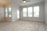 Located at 200 Governors Ct in Cartersville, Georgia, this single-floor residence offers a well-designed open-concept layout that connects the main living area to the kitchen. The kitchen is outfitted with rich dark cabinetry, granite-style countertops, a full suite of black appliances including a refrigerator, range, built-in microwave, and dishwasher, complemented by a tile backsplash and light hardwood-style flooring. A peninsula counter separates the kitchen from the living space, which features crown molding and a ceiling fan overhead.

The living and dining areas are finished with plush neutral carpeting and crown molding, while large windows invite generous natural light and outdoor views. The bedroom continues the carpeted flooring and is fitted with a ceiling fan and multiple windows that further enhance the bright, airy feel.

Two bathrooms echo the design language of the kitchen, each featuring dark wood vanities, granite-style countertops, and large mirrors. One bathroom includes a tub-shower combination. Both are finished with hardwood-style flooring for easy maintenance.

Storage is a highlight, with a generously sized walk-in closet equipped with extensive wire shelving on all sides, offering ample organization space. The overall ambiance is clean, functional, and move-in ready.