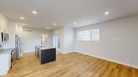Located at 516 North Main Street in Clawson, Michigan, this two-story residence offers a thoughtfully designed layout spread across two floors. The main level, which comprises the majority of the living space, centers around an open-concept kitchen and living room that creates a bright, airy atmosphere. The kitchen is a standout feature, equipped with white shaker cabinetry, stainless steel appliances including a refrigerator, range, and over-the-range microwave, and a striking granite-topped island with an undermount sink and modern gooseneck faucet. In-unit laundry is conveniently tucked nearby. Warm, light-toned hardwood-style flooring runs consistently throughout both levels, tying the home together with a clean, contemporary feel. Recessed lighting and neutral gray-white walls amplify the natural light that flows in through slatted windows. The two bedrooms are well-proportioned, with the primary bedroom offering a generously sized walk-in closet complete with built-in shelving and a natural light window. Both bathrooms are finished with granite vanity tops, white cabinetry, and matching hardwood-style flooring. The upper floor provides additional private living space, while hallways connecting the rooms ensure a smooth and functional flow throughout the home.