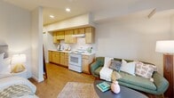 Located at 3097 SE Meek St in Milwaukie, Oregon, this studio apartment offers a thoughtfully designed single-floor layout that maximizes every inch of its space. The open-plan living and sleeping area is bathed in natural light from well-placed windows, creating a bright and welcoming ambiance throughout. Warm-toned hardwood-style flooring runs continuously through the main living space, lending a cohesive and clean aesthetic.

The galley-style kitchen lines one wall and features light wood cabinetry with ample upper and lower storage, white appliances including an electric range and full-size refrigerator, and a single-basin sink with white countertops. The kitchen flows seamlessly into the living area, making the space feel open and functional. Recessed lighting overhead keeps the kitchen well-illuminated.

The sleeping area is tucked toward the rear of the unit, benefiting from a large window with outdoor views and continued hardwood-style flooring. A dedicated closet provides organized storage. The full bathroom is finished with light wood cabinetry, a generous vanity with a wide mirror, white countertops, and neutral-toned flooring. The overall design is clean and modern, with a neutral color palette that makes the space feel calm and adaptable.