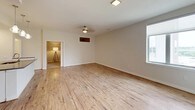 This single-floor residence offers two bedrooms and two bathrooms with a cohesive, modern design throughout. The open living area is finished with light wood-style flooring that extends toward large windows, allowing natural light to fill the space. A ceiling fan overhead and neutral-toned walls create a calm, airy atmosphere. The living area connects seamlessly to the kitchen, which features white cabinetry, dark quartz countertops, a subway tile backsplash, and a full suite of stainless steel appliances including a refrigerator, range, and built-in microwave.

A standout architectural detail is the sliding barn door, which provides a stylish and functional transition between the living space and the adjacent bedroom. Both bedrooms are carpeted in warm, neutral tones and include ceiling fixtures. One bedroom features a walk-in closet with built-in shelving, while another offers an elevated view through a well-positioned window.

The two bathrooms are finished with light wood-look tile flooring, white cabinetry, dark quartz countertops, and pendant lighting above large mirrors. One bathroom includes a frameless glass walk-in shower with built-in shelving, while the other provides a vanity with ample storage. The overall palette is clean and contemporary throughout.