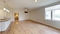 This single-floor residence offers two bedrooms and two bathrooms with a cohesive, modern design throughout. The open living area is finished with light wood-style flooring that extends toward large windows, allowing natural light to fill the space. A ceiling fan overhead and neutral-toned walls create a calm, airy atmosphere. The living area connects seamlessly to the kitchen, which features white cabinetry, dark quartz countertops, a subway tile backsplash, and a full suite of stainless steel appliances including a refrigerator, range, and built-in microwave.

A standout architectural detail is the sliding barn door, which provides a stylish and functional transition between the living space and the adjacent bedroom. Both bedrooms are carpeted in warm, neutral tones and include ceiling fixtures. One bedroom features a walk-in closet with built-in shelving, while another offers an elevated view through a well-positioned window.

The two bathrooms are finished with light wood-look tile flooring, white cabinetry, dark quartz countertops, and pendant lighting above large mirrors. One bathroom includes a frameless glass walk-in shower with built-in shelving, while the other provides a vanity with ample storage. The overall palette is clean and contemporary throughout.