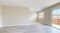 Located in Los Angeles' 90008 neighborhood, Unit 14 at 3910 Coco Ave is a well-appointed 2-bedroom, 1-bathroom unit spread across a single floor. The living room is a standout feature, bathed in natural light through a large sliding glass door that opens to a private outdoor balcony area, offering pleasant neighborhood views. Light gray wood-style flooring flows throughout the living spaces and bedrooms, contributing to a clean, cohesive aesthetic. The kitchen features a galley-style layout with white shaker cabinetry, dark countertops, stainless steel appliances including a refrigerator and dishwasher, and light tile flooring, offering an efficient and stylish space for meal preparation. Both bedrooms are well-sized, each equipped with ceiling fans, windows with blinds for natural light and privacy, and sliding-door closets providing ample storage. The primary bedroom offers a comfortable footprint suited for a full bedroom suite. The bathroom is finished with marble-style tile surrounding the shower/tub combo, white vanity cabinetry, and a dark countertop, echoing the design language found throughout the unit. A connecting hallway ties all rooms together in a functional and organized floor plan.