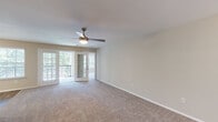 Located at 900 Golden Horseshoe Cir in Morrisville, NC, this single-floor residence offers a clean, neutral aesthetic with a thoughtful layout designed for comfortable everyday living. The open living area is anchored by plush carpeting, a ceiling fan with light fixture, and a bank of windows alongside a glass-panel door that leads to a private balcony, filling the space with natural light and outdoor views. The kitchen is well-appointed with white shaker-style cabinetry, light granite-look countertops, wood-look vinyl flooring, and black appliances including an electric range, built-in microwave, and dishwasher. A double-basin sink is positioned beneath a window, adding brightness to the workspace. The bedrooms continue the warm, carpeted aesthetic, each outfitted with ceiling fans and windows that invite natural light. Both full bathrooms feature wood-look vinyl flooring, white vanities with single-basin sinks, large mirrors, and tub-shower combinations. Generous closet space is present throughout, including walk-in style closets with built-in shelving. The overall ambiance is bright, clean, and move-in ready, with consistent finishes that create a cohesive and welcoming environment throughout.