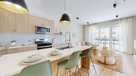 Located at 3001 W Belmont Ave in Chicago's vibrant Belmont-Cragin neighborhood, this thoughtfully designed 2-bedroom, 2-bathroom residence offers a bright, modern aesthetic across a well-utilized single floor. Light oak hardwood flooring runs throughout, tying the open-concept living spaces together seamlessly.

The kitchen is a standout feature, showcasing light wood cabinetry, a white subway tile backsplash, stainless steel appliances, and a generous island with a waterfall-edge countertop and bar seating for three — all anchored by striking black pendant lights with gold interiors. The kitchen flows directly into the living room, which is bathed in natural light from floor-to-ceiling sliding glass doors that open to a private balcony with neighborhood views. A built-in electric fireplace adds a refined focal point to the living area.

Both bedrooms are serene and well-lit, with large windows dressed in sheer curtains. The spacious primary bedroom comfortably accommodates a full suite of furnishings. The two bathrooms are finished with modern large-format tile, a wall-mounted toilet, and a tub-shower combination with decorative tile surround and black-framed glass enclosure, reflecting a clean, contemporary design sensibility throughout.