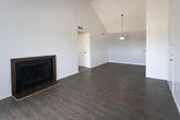 Located at 1601 N Lee Trevino Dr in El Paso, Texas, this single-floor unit offers a well-designed layout with a variety of appealing architectural details. The open-concept living and dining area is highlighted by soaring vaulted ceilings that create an expansive, airy feel, complemented by rich dark hardwood-style flooring throughout. A pendant light fixture adds a focal point to the dining area, while a wood-trimmed fireplace serves as a standout feature in the living room. Sliding glass doors lead to a private balcony with outdoor views, filling the space with natural light. The kitchen features dark wood cabinetry, light stone-look countertops, and includes a refrigerator and dishwasher, with a pass-through bar connecting it to the dining area. The bedrooms are carpeted for comfort, each equipped with ceiling fans and windows with blinds that allow for natural light and outdoor views. The bathrooms feature hardwood-style flooring, marble-patterned countertops, tiled tub-shower combinations, and mirrored vanities. Neutral white walls throughout the unit provide a clean, versatile canvas, while textured ceilings add subtle character to each room.