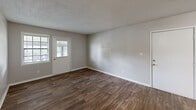Located at 2130 Westmead Dr SW in Decatur, Alabama, this one-bedroom, one-bathroom home offers a practical and well-appointed single-floor layout. The combined kitchen and living room serves as the heart of the home, featuring rich wood-look flooring, neutral gray walls, and a front-facing window and door that invite natural light into the open space. The kitchen is outfitted with white cabinetry, sleek silver hardware, and light granite-style countertops, offering ample storage and workspace. A dedicated laundry area is conveniently tucked adjacent to the kitchen, complete with a full-size washer and dryer. The bedroom is a comfortable, well-proportioned room with the same wood-look flooring, neutral tones, a textured ceiling, and a window that brings in natural light. A hallway connects the bedroom to a closet and the full bathroom, which features a tub-shower combination, a white vanity with a clean countertop, wood-look tile flooring, and brushed nickel fixtures. Throughout the home, consistent use of neutral colors, white trim, and wood-look flooring creates a cohesive and clean aesthetic, making this an efficient and move-in ready space.