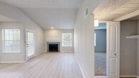 Located at 2615 Spanish Trail in Arlington, TX, this single-story home offers a well-organized layout designed for comfortable everyday living. The living room serves as the central gathering space, featuring light wood-style flooring, vaulted ceilings with a textured finish, multiple windows that invite natural light, and a tiled fireplace with a white mantel as a focal point. The neutral color palette throughout creates a clean, cohesive aesthetic.

The kitchen is thoughtfully equipped with gray cabinetry, white quartz-style countertops, a subway tile backsplash, and a full suite of stainless steel appliances including an electric range, over-the-range microwave, and refrigerator. A peninsula with an integrated sink and breakfast bar provides additional workspace and casual dining options. Light wood-style flooring continues seamlessly from the living area into the kitchen.

The bedrooms are carpeted for comfort, with one featuring a ceiling fan and direct access to a bathroom. Windows in each bedroom allow for natural light and outdoor views. The bathroom includes a tiled tub-and-shower combination, modern vanity with a white countertop, and light wood-style flooring, maintaining the home's consistent, updated aesthetic throughout.