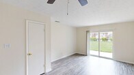 This one-bedroom, one-bathroom unit in North Augusta, South Carolina offers a practical and well-laid-out single-floor design. The living room is bright and open, featuring durable wood-look plank flooring, a ceiling fan, and a sliding glass door that fills the space with natural light and provides views of the surrounding greenery. The layout flows naturally from the living area into the kitchen and hallway. The kitchen is efficiently designed with white cabinetry, a subway tile backsplash, light-toned countertops, a double coil electric range, and a full-size refrigerator, along with a window that brings in additional natural light. A hallway connects the main living areas to the private bedroom and bathroom. The bedroom is a comfortable size, complete with a ceiling fan, a large window overlooking the outdoors, and access to a dedicated closet. The bathroom features a clean, all-white tub and shower combination. Textured ceilings are found throughout, and consistent wood-look flooring runs across the main living spaces, giving the unit a cohesive and tidy appearance. This unit offers a straightforward, functional layout well-suited for single occupancy or a couple.