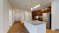 Located at 2098 Seminole Blvd in Largo, Florida, this single-floor residence offers a thoughtfully designed open-concept layout that blends functionality with modern style. Rich hardwood-style flooring extends throughout the main living areas, creating a warm and cohesive aesthetic that ties the space together.

The kitchen serves as a central focal point, showcasing rich dark wood cabinetry, a mosaic tile backsplash, and a full suite of stainless steel appliances including a refrigerator, range, and microwave. A peninsula island with a granite-style countertop and an undermount sink provides additional prep space and a natural gathering point, accented by sleek pendant lighting overhead.

The open living area adjoins the kitchen seamlessly, offering generous square footage and a clean, neutral palette that allows for versatile furnishing arrangements. Natural light filters in through multiple windows, brightening the space throughout the day.

The bedroom features plush wall-to-wall carpeting, a ceiling fan, and windows that invite natural light, creating a comfortable and restful retreat. A dedicated closet offers ample storage. A hallway connects the bedroom to the main living area, with access to additional storage and a convenient in-unit laundry area housing a side-by-side washer and dryer. The overall layout is efficient, practical, and well-suited for comfortable everyday living.