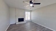 This single-story, 2-bedroom, 2-bathroom home in Midland, TX offers a well-organized layout with a comfortable mix of hard-surface and carpeted flooring throughout. The living room serves as the heart of the home, showcasing gray wood-look vinyl plank flooring, a textured ceiling, a ceiling fan with light, and a striking white-painted brick fireplace flanked by a shiplap accent surround. A large window brings in natural light, creating a bright and welcoming atmosphere. The open flow leads into the kitchen, which is equipped with stainless steel appliances, including a refrigerator, range, and over-the-range microwave, complemented by dark cabinetry and vinyl plank flooring. Both bedrooms feature plush carpet, ceiling fans, and ample natural light, with the primary bedroom offering direct access to the outdoors through a door framed by windows. Each bedroom is served by a dedicated closet. The two bathrooms are thoughtfully updated with white cabinetry, quartz-style countertops, undermount sinks, matte black hardware and fixtures, and tub-shower combinations, with one bathroom featuring a round mirror and a transom window for added brightness. The neutral gray color palette and modern finishes create a cohesive and move-in-ready feel throughout the home.