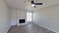 This single-story, 2-bedroom, 2-bathroom home in Midland, TX offers a well-organized layout with a comfortable mix of hard-surface and carpeted flooring throughout. The living room serves as the heart of the home, showcasing gray wood-look vinyl plank flooring, a textured ceiling, a ceiling fan with light, and a striking white-painted brick fireplace flanked by a shiplap accent surround. A large window brings in natural light, creating a bright and welcoming atmosphere. The open flow leads into the kitchen, which is equipped with stainless steel appliances, including a refrigerator, range, and over-the-range microwave, complemented by dark cabinetry and vinyl plank flooring. Both bedrooms feature plush carpet, ceiling fans, and ample natural light, with the primary bedroom offering direct access to the outdoors through a door framed by windows. Each bedroom is served by a dedicated closet. The two bathrooms are thoughtfully updated with white cabinetry, quartz-style countertops, undermount sinks, matte black hardware and fixtures, and tub-shower combinations, with one bathroom featuring a round mirror and a transom window for added brightness. The neutral gray color palette and modern finishes create a cohesive and move-in-ready feel throughout the home.