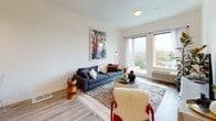 This single-floor unit offers a well-designed layout that maximizes functionality and comfort throughout. The open-concept kitchen is a standout feature, outfitted with warm honey-toned cabinetry, stainless steel appliances including a range, microwave, and refrigerator, and a white subway tile backsplash. A generous white quartz island provides bar seating, making it ideal for casual dining or entertaining. Recessed lighting and a pendant fixture add dimension to the space.

The living area is bathed in natural light from large windows that frame outdoor treetop views, creating a bright and welcoming atmosphere. Light wood-tone flooring runs consistently throughout, tying the spaces together cohesively.

The bedroom offers a calm retreat, featuring a sliding-door closet with built-in shelving and a hanging rod for ample storage. Adjacent, the hallway leads to a stacked washer and dryer conveniently tucked into a dedicated laundry nook.

The bathroom is clean and straightforward, featuring a full tub and shower combo with chrome fixtures, a toilet, and wood-look flooring that complements the rest of the unit. The overall aesthetic is modern and neutral, emphasizing clean lines and practical living.