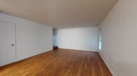 The Coventry in Memphis, Tennessee is a two-story, 3-bedroom, 2-bathroom home that offers a practical and comfortable layout across two well-proportioned floors. The main level features a spacious living room with warm hardwood flooring, neutral white walls, a textured ceiling, and windows that allow natural light to fill the space. The living area flows openly toward the kitchen, which is equipped with wood cabinetry, dark granite-style countertops, black appliances including an electric range and dishwasher, and hardwood flooring that continues throughout the main level. A hallway and staircase connect the two floors seamlessly. The main level also includes a bathroom with wood vanity, granite countertop, and a full shower-tub combination. Upstairs, the three bedrooms are carpeted in a warm neutral tone. The generously sized primary bedroom features striking vaulted ceilings with exposed beams and a window for natural light, creating an airy and distinctive atmosphere. The additional bedrooms are well-sized, with one featuring a closet and direct hallway access. The upper level also includes a half bath with hardwood flooring. Throughout the home, clean white walls, consistent finishes, and a straightforward design create a functional and inviting living environment.