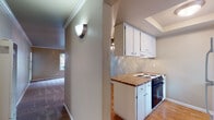 Located at 36000 Fremont Blvd in Fremont, California, this single-floor unit offers a functional and comfortable layout with a thoughtful blend of flooring materials and a well-connected living space. The open-concept design connects the kitchen and living area seamlessly, creating a spacious and inviting atmosphere. The kitchen features a peninsula with laminate countertops, white cabinetry, a built-in electric cooktop, and a full-size refrigerator, all set atop warm hardwood-style flooring. A ceiling fan overhead adds both style and practicality to the shared living and kitchen zone. Crown molding details throughout lend a classic finishing touch to the interior. The living room is generously sized with soft carpeting, large windows that invite ample natural light, and a sliding glass door providing direct outdoor access and views of surrounding greenery. The bedroom offers plush carpeting, crown molding, and a sliding-door closet with built-in shelving for organized storage. The bathroom is equipped with a clean, full-size soaking tub and shower combination, complemented by a frosted window for natural ventilation. Wall sconces and ceiling fixtures provide warm ambient lighting throughout the unit, contributing to an overall cozy and welcoming ambiance.