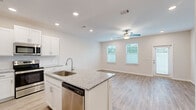 Located at 234 Shoremont Dr in Santa Rosa Beach, FL, this two-story home offers a well-designed layout spread across two floors. The main level features an open-concept kitchen and living area, filled with natural light from multiple windows and finished with light wood-look flooring throughout. The kitchen is a standout space, showcasing white shaker cabinetry, granite countertops, a center island with an undermount sink, and a full suite of stainless steel appliances including a refrigerator, range, microwave, and dishwasher. The adjacent living area is bright and airy, with recessed lighting and a ceiling fan overhead. Upstairs, the upper floor hosts both bedrooms, each carpeted and equipped with ceiling fans. The generously sized primary bedroom includes access to a walk-in closet with wire shelving. Three bathrooms serve the home, with the bathrooms featuring granite-topped vanities with white cabinetry, large mirrors, and tub-shower combinations. A dedicated laundry room on the upper floor includes a full-size washer and dryer. The home's clean, neutral palette and modern finishes create a bright, move-in-ready atmosphere throughout.