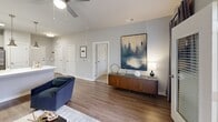 Located at 13100 Margie Ln in Raleigh, NC, this thoughtfully designed one-bedroom, one-bathroom residence offers a functional and stylish single-floor layout. The open-concept living and dining area is anchored by warm hardwood-style flooring, a ceiling fan, and large windows that invite abundant natural light. A glass-paned door leads to a private balcony, extending the living space outdoors.

The kitchen is a standout feature, boasting light wood cabinetry, white subway tile backsplash, crisp quartz countertops, and a peninsula with pendant lighting overhead. Stainless steel appliances — including a refrigerator, range, microwave, and dishwasher — complete the space, along with an adjacent pantry for added storage.

The bedroom is a comfortable retreat with plush carpet, a ceiling fan, and generous natural light from multiple windows. Two closets provide ample storage. The bathroom features wood-look tile flooring, a full tub-shower combination with white subway tile surround, and a vanity with modern cabinetry.

Additional practical spaces include a dedicated laundry room and utility room. The neutral gray palette and modern finishes throughout create a cohesive, contemporary ambiance suited to everyday living in Raleigh.