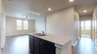 Located at 4835 Lord Rd in San Antonio, TX, this single-story unit offers a thoughtfully designed open-concept layout with modern finishes throughout. The kitchen is a standout feature, showcasing dark espresso cabinetry, granite-style countertops, and a full suite of black appliances including a range, microwave, refrigerator, and dishwasher. A central island with a double-basin sink and additional counter space connects seamlessly to the living area, which is enhanced by recessed lighting, a ceiling fan, and wood-look flooring that extends throughout the main living spaces. The living room benefits from natural light through multiple windows, creating a bright and welcoming atmosphere. Bedrooms are carpeted for comfort, with generous natural light provided by double windows fitted with blinds. At least one bedroom includes a spacious walk-in closet outfitted with wire shelving systems for ample storage. The bathrooms feature the same dark cabinetry as the kitchen, paired with white countertops, large mirrors, wood-look flooring, and a tub-shower combination. A dedicated vanity area in the primary bath adds a functional touch. The overall design maintains a consistent, contemporary aesthetic with neutral tones and cohesive finishes from room to room.