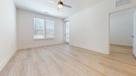 This 670-square-foot, one-bedroom, one-bathroom apartment is designed with a clean, modern aesthetic throughout its single floor. Light-toned hardwood flooring extends continuously across all rooms, creating a cohesive and airy feel. Crisp white walls and white baseboards enhance the brightness of the space.

The open-concept kitchen and living area serves as the heart of the unit. The kitchen features gray shaker-style cabinetry with gold hardware, a white quartz peninsula countertop, stainless steel appliances including a refrigerator, microwave, and range, recessed lighting, and pendant lights above the peninsula. The living area benefits from a ceiling fan and direct access to an exterior door, allowing natural light to flow in through multiple windows fitted with horizontal blinds.

The primary bedroom measures 140 square feet and includes a ceiling fan, two windows with exterior views, and direct access to the full bathroom. The bathroom is appointed with a dual-sink vanity featuring gray cabinetry, white quartz countertops, chrome fixtures, a large mirror, and a tiled tub-shower combination. A walk-in closet is accessible from the bathroom, adding practical storage to the unit.