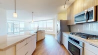 Located in the heart of downtown Phoenix at 44 W Monroe St, this high-rise residence offers one bedroom, two bathrooms, and a generous open floor plan bathed in natural light. Floor-to-ceiling windows span the living room and bedroom, framing sweeping panoramic views of the Phoenix skyline and surrounding desert cityscape. The living area flows seamlessly onto a private balcony, extending the living space outdoors with remarkable vistas.

The contemporary kitchen is a standout feature, showcasing a large central island with a quartz countertop and integrated sink, complemented by sleek white lower cabinetry and warm wood-toned upper cabinets. A marble-style tile backsplash, stainless steel appliances including a gas range, oven, microwave, and refrigerator, along with track and pendant lighting, complete the culinary space. Light hardwood flooring runs throughout the entire residence, lending warmth and continuity.

The spacious bedroom captures the same sweeping city views through oversized windows. It is served by a generous walk-in closet with built-in shelving. Two full bathrooms provide ample convenience. A stacked in-unit washer and dryer adds everyday practicality. The clean, neutral palette and modern finishes throughout create a bright, polished urban living environment.