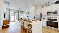 Located in Phoenix, AZ, this well-appointed 1-bedroom, 1-bathroom single-story home offers a thoughtfully designed open-concept layout that maximizes every square foot. Light wood flooring flows consistently throughout, lending warmth and cohesion to the interior.

The kitchen is a standout feature, showcasing crisp white shaker cabinetry, a classic subway tile backsplash, quartz countertops, a central island with seating, pendant lighting, and a full suite of stainless steel appliances. It opens seamlessly into the living area, creating an ideal space for daily living and entertaining.

The living room is bright and airy, with large sliding glass doors and additional windows that invite abundant natural light and provide direct access to a private outdoor patio. The patio extends the living space outdoors with lush greenery and room for outdoor dining.

The bedroom is a serene retreat, featuring light-filled windows with blinds and drapes, light wood flooring, and a comfortable, neutral aesthetic. The full bathroom is efficiently laid out with white cabinetry, a broad vanity with quartz countertops, and a glass-enclosed shower area. A dedicated walk-in closet adds practical storage. The home's clean, modern design and bright, neutral palette create a welcoming and tranquil ambiance throughout.
