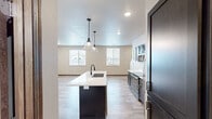 This well-appointed two-story home offers a thoughtful layout across two floors, combining modern design with practical functionality. The main floor hosts an open-concept kitchen and living area filled with natural light from multiple windows. The kitchen is a standout feature, centered around a dark-based island with a white quartz countertop, undermount sink, and stylish pendant lighting. Dark espresso cabinetry lines the walls, complemented by stainless steel appliances including a range, microwave, and refrigerator. Light wood-look flooring ties the space together seamlessly. A utility room and hallway complete the main level. Upstairs, the primary bedroom is a generously sized retreat finished with plush carpet, a ceiling fan, and windows offering neighborhood views. It includes a dedicated walk-in closet with built-in shelving and hanging rods, providing ample storage. The second bedroom is equally spacious with recessed lighting and durable wood-look flooring. Two full bathrooms serve the home, featuring dark cabinetry vanities, white countertops, and tile-look flooring. Neutral tones, wood trim accents, and recessed lighting throughout create a clean, contemporary ambiance suitable for comfortable everyday living.