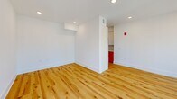 Located at 619 N Broad Street in Philadelphia's dynamic Northern Liberties neighborhood, this one-bedroom, two-bathroom unit offers a thoughtfully designed layout across a single floor. Natural hardwood flooring flows throughout the main living areas, complemented by crisp white walls and recessed lighting that create a bright, modern atmosphere.

The galley-style kitchen is a standout feature, showcasing warm terracotta-orange lower cabinetry paired with white upper cabinets, light quartz countertops, a sleek tile backsplash, and a brass gooseneck faucet over a stainless steel sink. Stainless steel appliances, including a full-size refrigerator, complete the well-appointed space.

The open living room is flooded with natural light through a bank of large windows fitted with dark roller shades, offering elevated views of the Philadelphia cityscape. The bedroom features plush carpeting, a generous closet, and its own window with urban views.

The two bathrooms each bring distinct character: one features bold, graduated orange-and-cream square tiles surrounding a soaking tub with dark bronze fixtures, while the second offers a wood-toned vanity with matte black hardware and neutral tile flooring. A connecting hallway with hardwood floors ties the space together efficiently.