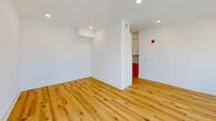 Located at 619 N Broad Street in Philadelphia's dynamic Northern Liberties neighborhood, this one-bedroom, two-bathroom unit offers a thoughtfully designed layout across a single floor. Natural hardwood flooring flows throughout the main living areas, complemented by crisp white walls and recessed lighting that create a bright, modern atmosphere.

The galley-style kitchen is a standout feature, showcasing warm terracotta-orange lower cabinetry paired with white upper cabinets, light quartz countertops, a sleek tile backsplash, and a brass gooseneck faucet over a stainless steel sink. Stainless steel appliances, including a full-size refrigerator, complete the well-appointed space.

The open living room is flooded with natural light through a bank of large windows fitted with dark roller shades, offering elevated views of the Philadelphia cityscape. The bedroom features plush carpeting, a generous closet, and its own window with urban views.

The two bathrooms each bring distinct character: one features bold, graduated orange-and-cream square tiles surrounding a soaking tub with dark bronze fixtures, while the second offers a wood-toned vanity with matte black hardware and neutral tile flooring. A connecting hallway with hardwood floors ties the space together efficiently.