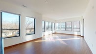 This thoughtfully designed single-floor unit offers a seamless blend of modern finishes and functional living spaces throughout. The open-concept living and dining area is a standout feature, bathed in abundant natural light streaming through a generous wraparound arrangement of large, black-framed windows that frame views of the surrounding neighborhood. Rich hardwood-style flooring flows throughout the main living areas, complementing the warm wood trim details found across the unit.

The kitchen is well-equipped for everyday living, featuring warm wood cabinetry, sleek dark granite countertops, a kitchen island, and a full suite of stainless steel appliances including a French door refrigerator, electric range, and built-in microwave. The space transitions effortlessly into the main living area, making it ideal for entertaining.

The bedrooms are carpeted for comfort and feature natural light and ample closet space, including a walk-in closet outfitted with wire shelving. Two full bathrooms serve the unit — one featuring a soaking tub and shower combination with a warm wood vanity and tile flooring, and a second en-suite bathroom with a glass-enclosed walk-in shower and matching tile floors. A dedicated in-unit laundry area with a full-size washer and dryer adds everyday convenience to this well-appointed space.