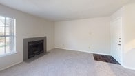 This single-floor residence offers a thoughtfully arranged layout across several distinct living areas. The living room serves as a central gathering space, featuring plush wall-to-wall carpeting, neutral-toned walls, and a classic fireplace with a dark surround — an ideal focal point for relaxed living. Adjacent to the living area, the dining room benefits from natural light streaming through a large window and sliding glass door, while an elegant chandelier adds a refined touch overhead.

The kitchen is designed for both functionality and style, showcasing a peninsula with granite countertops and an integrated sink, dark cabinetry with ample storage, a white subway tile backsplash, and a full suite of stainless steel appliances including a range, microwave, and refrigerator. A louvered-door closet is conveniently located nearby.

The bedroom is a quiet, carpeted retreat with soft neutral walls and a window fitted with blinds, allowing for natural light and privacy. The full bathroom is finished with dark wood-tone cabinetry, a granite vanity top, an undermount sink with brushed nickel fixtures, wood-look flooring, and a tub-shower combination with clean white tile surround. Together, these spaces form a cohesive and comfortable single-level home.