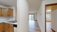 Located at 802 W Main St in Waunakee, Wisconsin, this one-bedroom, one-bathroom unit offers a well-organized single-level layout that makes efficient use of its space. The open-concept kitchen and living area form the heart of the unit, connected by a peninsula with a built-in sink and white countertops that doubles as a breakfast bar. The kitchen features warm oak cabinetry, a white electric range, dishwasher, refrigerator, and a range hood, all set above light wood-style plank flooring that flows throughout the entire unit. The living room is bright and welcoming, illuminated by natural light pouring in through a large sliding glass door fitted with vertical blinds, which opens to an outdoor view of surrounding greenery. A ceiling fan adds comfort to the living space. The bedroom is a comfortable size, with its own window with vertical blinds allowing in natural light, a dedicated closet, and consistent light wood-style flooring. The bathroom is generously proportioned, featuring tile flooring, a walk-in shower equipped with grab bars, a soaking tub, and warm wood-toned cabinetry. Clean white walls and neutral finishes throughout give the unit a calm, cohesive aesthetic.