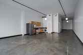 Located at 620 S Main St in the heart of Downtown Los Angeles, this single-floor loft-style unit showcases an industrial-modern aesthetic throughout. The open-plan living area is defined by polished concrete floors that extend seamlessly across the entire space, soaring ceilings, and crisp white walls that amplify the sense of volume and light. Globe pendant lights and track lighting along exposed black rails provide a clean, contemporary feel that complements the loft's minimalist character.

Floor-to-ceiling windows along one wall flood the main living area with natural light and frame dynamic views of the surrounding Downtown Los Angeles streetscape. The kitchen is efficiently designed with warm wood cabinetry, dark granite countertops, stainless steel appliances including a gas range, refrigerator, and dishwasher, as well as an in-unit washer and dryer. The bathroom features a combination tub and shower with a bold black-and-white tile surround, a dark vanity, and polished stone-look flooring. Black baseboards throughout the unit provide a sharp contrast to the white walls, reinforcing the space's modern industrial character. This loft offers a versatile, gallery-like environment ideal for live-work or residential use in a prime urban location.