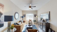This single-story, 2-bedroom, 1-bathroom home offers a thoughtfully designed layout that maximizes comfort and functionality. The living room serves as the heart of the space, featuring light wood-style flooring, neutral warm-toned walls, and multiple windows fitted with blinds that allow natural light to filter in. A ceiling fan overhead adds both style and practicality, while the elongated layout provides ample room for seating and décor arrangements.

The kitchen is a standout feature, showcasing dark espresso cabinetry that extends to the upper walls, providing generous storage space. Black appliances, including a range, microwave, dishwasher, and refrigerator, complement the cabinetry, while light countertops provide contrast. A breakfast bar offers additional seating and workspace.

Both bedrooms are comfortably sized, each featuring plush carpet flooring, ceiling fans, windows with natural light, and closet access. The rooms offer a calm, restful atmosphere with neutral wall tones.

The bathroom includes dark vanity cabinetry with a light countertop, a large mirror with overhead lighting, tile flooring, and a shower-tub combination. The single-floor layout ensures easy accessibility and a cohesive flow throughout the entire home.