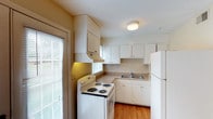 This two-story, 2-bedroom, 2-bathroom home offers a thoughtfully arranged layout designed for comfortable everyday living. The kitchen features white cabinetry that extends to the ceiling for ample storage, complemented by light granite-style countertops and classic white appliances, including a coil-burner range and a full-size refrigerator. A stainless steel sink is positioned beneath a window that invites natural light into the space. The warm hardwood-style flooring adds a welcoming touch to the kitchen area. Blinds on the windows provide privacy while still allowing natural light to filter through. The two-floor layout allows for a natural separation between living and sleeping areas, offering both functionality and privacy. With two full bathrooms, the home accommodates the needs of multiple occupants with ease. The overall aesthetic is clean and neutral, with light-toned walls and white finishes throughout the kitchen that create a bright, airy atmosphere. This home presents a practical and comfortable living environment, well-suited for those seeking a straightforward, move-in-ready space with a classic design sensibility.