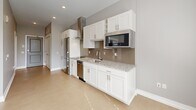 Located at 50 College Ave SE in Grand Rapids, Michigan, this compact and thoughtfully designed unit makes excellent use of its single-floor layout. The open-concept main area seamlessly combines the living, dining, and kitchen spaces into one cohesive room, finished with light-toned tile flooring and neutral gray walls that create a clean, modern aesthetic throughout.

The kitchen is well-appointed with white shaker-style cabinetry, granite countertops with a tile backsplash, and a full suite of stainless steel appliances including a refrigerator, dishwasher, gas range, built-in microwave, and a stainless steel wall-mounted range hood. The open layout allows the kitchen to flow naturally into the dining and living area, which receives natural light through a window with blinds.

A closet near the entry houses a stacked washer and dryer unit, providing the convenience of in-unit laundry. The full bathroom features a combination tub and shower, a white vanity with a stone-top countertop and sink, and consistent light flooring that ties the space together. Recessed lighting throughout the unit ensures bright, even illumination. The overall design emphasizes clean lines, functional storage, and modern finishes, making this a practical and stylish urban living space.