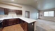 Located at 4760 Timber Pkwy S in Fargo, ND, this two-bedroom, two-bathroom unit offers a thoughtfully designed single-floor layout with a comfortable and functional living environment. The open-concept kitchen is a standout feature, showcasing rich dark-wood cabinetry, white countertops, stainless steel appliances including a refrigerator, microwave, and range, and a peninsula island that provides additional workspace and a natural transition into the living area. Vaulted ceilings in the main living and kitchen areas enhance the sense of openness and airiness throughout. The spacious living room features plush carpeting, a wall-mounted A/C unit, baseboard heating, and a door with access to an outdoor area, along with a large window that invites natural light and exterior views. Both bedrooms are well-proportioned and carpeted, each with windows overlooking the surrounding neighborhood and baseboard heating for year-round comfort. Each bedroom is served by its own closet, with walk-in configurations offering wire shelving for organized storage. The two bathrooms include tub/shower combos with clean, bright surrounds. A dedicated in-unit laundry room with side-by-side washer and dryer and overhead shelving adds everyday convenience to this practical and comfortable Fargo residence.