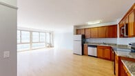 Located at 2933 N Sheridan Road in Chicago's vibrant Lakeview neighborhood, this well-appointed unit offers a thoughtfully designed single-floor layout with a clean, modern aesthetic. Light hardwood floors run throughout the entire space, creating a warm and cohesive feel from room to room.

The open-concept living and dining area is generously proportioned, bathed in natural light streaming through a wide bank of floor-to-ceiling windows that frame views of the surrounding cityscape. The airy layout provides ample flexibility for furnishing and arrangement.

The kitchen is a functional highlight of the unit, featuring rich warm-toned wood cabinetry, granite countertops, a white subway tile backsplash, and a full suite of stainless steel appliances including a range, microwave, and dishwasher. A built-in desk area adds practical workspace directly within the kitchen.

The bedroom is a well-sized, sun-filled retreat with the same hardwood flooring and large windows offering continued city views. A mirrored sliding-door closet enhances the sense of space, while a connected bathroom provides convenient en-suite access. The overall ambiance of the unit is bright, clean, and move-in ready, well-suited for those seeking a comfortable urban residence in one of Chicago's most sought-after neighborhoods.
