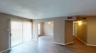 This single-story unit in Houston, Texas offers a well-organized layout comprising one bedroom, one bathroom, and a dedicated study. Wood-style flooring flows consistently throughout the living areas, complementing the neutral warm-gray wall tones that create a cohesive, understated aesthetic. Textured ceilings add a classic touch across the space.

The living area is generously proportioned, benefiting from a sliding glass door that opens to a private patio, allowing natural light to fill the room. Vertical blinds provide adjustable light control. An open passageway connects the living area to the study, which features its own ceiling fan and window with blinds, making it a versatile space suitable for a home office or additional lounge area.

The galley-style kitchen is efficiently designed with gray cabinetry, speckled countertops, a stainless steel sink, track lighting, and black appliances including a full-size refrigerator. A pass-through counter connects the kitchen to the adjacent living space.

The bedroom provides a comfortable retreat with a ceiling fan, a window for natural light, and access to a walk-in closet offering ample storage. An additional double-door closet provides further storage options nearby.

The bathroom features speckled countertops, a wide vanity, mirrored medicine cabinets, and wood-style flooring, maintaining the consistent design language found throughout the unit.