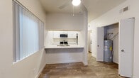 Located at 5919 N Oracle Rd in Tucson, Arizona, this single-floor, 4-bedroom, 2-bathroom home offers a clean, modern aesthetic throughout. The open layout connects a living area to a pass-through kitchen featuring white shaker cabinetry, light stone countertops, a breakfast bar, and stainless steel appliances including a range and microwave. A second kitchen provides added functionality. Wood-look flooring runs through the main living areas, complementing the bright, neutral-toned walls and creating a cohesive feel across the space. The primary bedroom is generously sized, featuring large sliding glass doors dressed with vertical blinds that invite natural light and provide outdoor access. A dedicated bathroom with a full tub-shower combo and brushed nickel fixtures serves the home alongside a second full bathroom. The secondary bedrooms are carpeted and each includes closet storage. A hallway area houses a stacked washer and dryer unit alongside built-in shelving, adding convenient in-unit laundry. The overall ambiance is light, clean, and functional, with a straightforward single-level floor plan well-suited for practical everyday living in the Tucson area.