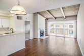 Located at 200 City Blvd W in Orange, CA, this single-story home showcases a mid-century-inspired design highlighted by distinctive exposed wood beam ceilings found throughout the living areas and bedrooms. The spacious living room is a standout, featuring a classic fireplace with a white marble surround, wide-plank wood-style flooring, and large sliding glass doors that open to a private balcony overlooking lush greenery, flooding the space with natural light. The kitchen has been thoughtfully updated with white shaker cabinetry, sleek marble-look countertops and backsplash, stainless steel appliances including a range, microwave, and dishwasher, and plantation shutters that offer both style and privacy. A pendant light anchors the adjacent dining area, which connects seamlessly to the kitchen via an open passthrough. The bedrooms continue the exposed beam aesthetic, featuring wood-paneled ceilings, plush carpeting, and plantation-shuttered windows. The bathrooms are clean and functional, with a glass-enclosed shower and white vanity cabinetry. Wood-style flooring flows throughout the main living areas, tying together a cohesive and well-appointed interior.
