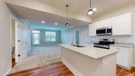 Located at 6650 Liberty Grand Blvd. in Powell, Ohio, this well-appointed two-story home offers a thoughtfully designed layout across two levels. The main floor showcases an open-concept design where the kitchen flows seamlessly into the living area, creating an inviting and functional space for everyday living and entertaining. The kitchen is a standout feature, equipped with white shaker-style cabinetry, granite countertops, and a large center island with an undermount sink. Stainless steel appliances, including a range, built-in microwave, and refrigerator, complement the space, while stylish pendant lighting adds a contemporary touch. Rich hardwood flooring extends throughout the main living areas, transitioning to plush carpet in the living room and upper level. A half bath with hardwood flooring is conveniently located on the main floor. Upstairs, the home includes carpeted bedrooms bathed in natural light from generously sized windows. The primary bedroom features vaulted ceilings and a spacious walk-in closet outfitted with wire shelving and storage racks. A dedicated laundry area with a full-size washer and dryer rounds out the upper level, adding practical convenience to the home's overall design.