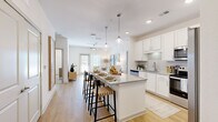 Located at 12020 Brush Hill Rd in Wildwood, Florida, this thoughtfully designed 2-bedroom, 2-bathroom residence offers a bright, modern living experience on a single floor. The open-concept layout connects the kitchen, dining, and living areas seamlessly, creating an inviting and functional space. The kitchen is a standout feature, showcasing white shaker cabinetry, granite countertops, stainless steel appliances, and a central island with pendant lighting and bar seating — ideal for casual dining and entertaining. Light wood-style flooring flows throughout the main living areas, enhancing the airy, contemporary aesthetic. The living room receives abundant natural light through large windows and a glass door, adding warmth and openness to the space. Both bathrooms are finished with granite vanity countertops, white cabinetry, and wood-look flooring. One bathroom features a walk-in shower, while the other includes a tub-shower combination. The spacious primary bedroom offers a ceiling fan, direct bathroom access, and a generously sized walk-in closet with wire shelving. The second bedroom is equally well-lit, with large windows and a ceiling fan. Throughout, the residence maintains a clean, neutral palette with modern finishes that convey a sense of comfort and quality.