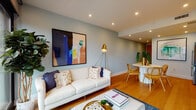 This contemporary two-floor residence combines thoughtful design with high-end finishes to create an inviting and functional living environment. The open-concept living and dining area is anchored by soft blue-gray walls, warm hardwood flooring, and recessed lighting, flowing seamlessly into a sleek, galley-style kitchen outfitted with stainless steel appliances, a marble-style backsplash, flat-panel cabinetry in a mix of white and natural wood tones, and a waterfall-edge countertop. Floor-to-ceiling windows in the living area frame expansive views of the surrounding cityscape, filling the space with abundant natural light. The bedrooms are generously proportioned, each featuring walk-in closets with custom built-in storage and sliding mirrored doors. One bedroom is distinguished by a bold teal accent wall paired with large-format windows offering sweeping urban views, while another showcases warm blush tones alongside a well-organized walk-in closet. The bathrooms are finished with elegant marble-look tile from floor to ceiling, floating wood vanities with white vessel sinks, glass-enclosed walk-in showers, and illuminated mirrors, lending a spa-like quality to the space. Throughout both floors, the consistent use of hardwood flooring, curated artwork, and modern fixtures contributes to a cohesive, sophisticated aesthetic.